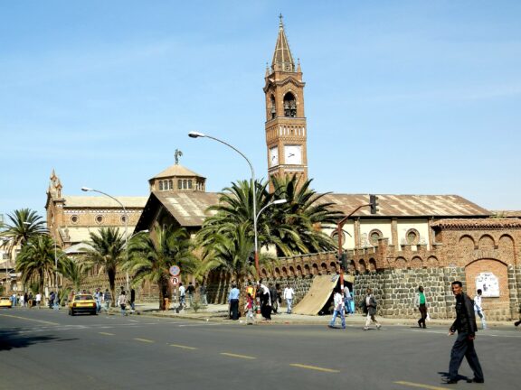 A street view in Eritrea, Africa, depicts people and a notable clock tower, hinting at a significant local landmark.