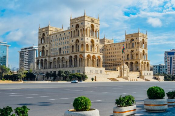 The Government House of Azerbaijan in Baku features ornate architecture, multiple balconies and towers, against a clear blue sky.