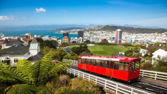 A red cable car in Wellington with a panoramic view of the city and ocean in the background.