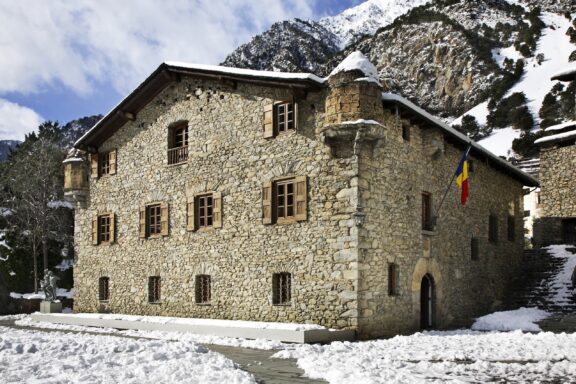 Stone Building with Snow-Covered Roof and Mountain Background Andorra la vella principality of andorra 09 february 2013 :