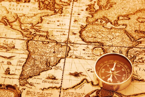 A compass sits on an old map showing the line of the equator.