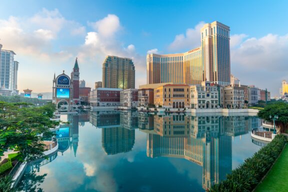 Venetian hotel and casino with surrounding buildings in Macau reflection in the water under cloudy blue sky, China