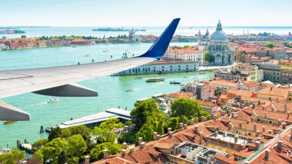 Plane flies over Venice, Italy, Europe. Aerial view of city and sea from airplane window. Flight above Venice near airport during taking off or landing. Concept of vacation, tourism and travel.