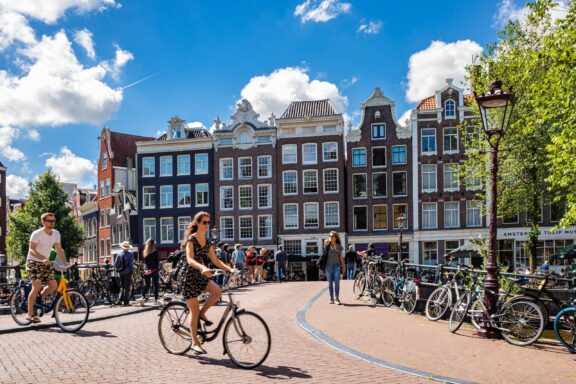 People ride bicycles on a sunny day in Amsterdam, the capital of the Netherlands. 