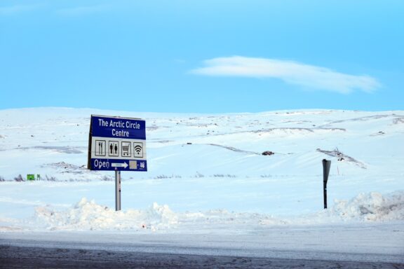 Arctic circle road in Norway. Landscape covered in snow with a sign showing the "Arctic Circle Centre".