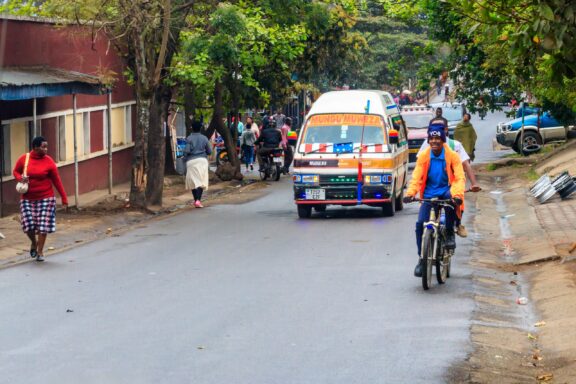 People and vehicles travel along a street in Arusha, Tanzania