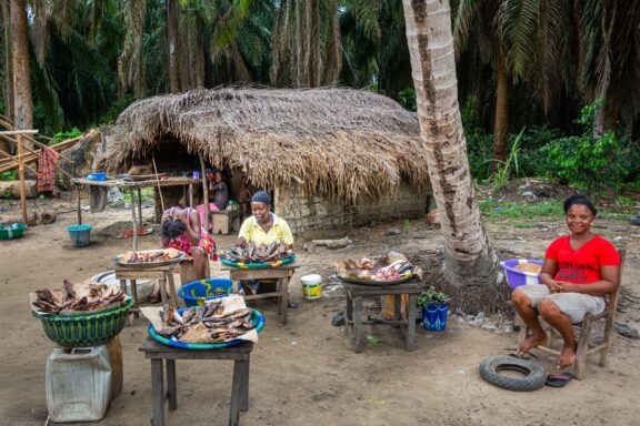 People sit around dried fish at a traditional rural market in Bensonville, Liberia.