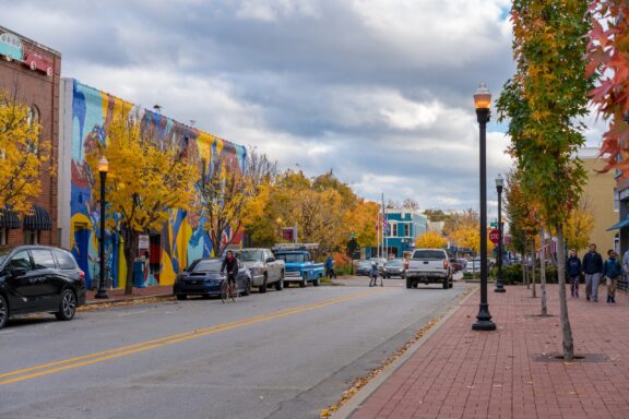 People and cars pass on a street in downtown Bentonville, Arkansas on a cloudy day. 