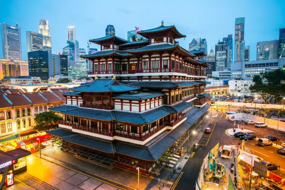 Dusk View of Traditional Architecture in Chinatown, Singapore with Modern Skyline in the Background A backdrop of skyscrapers can be seen behind the Buddha Tooth Relic Temple in Singapore's Chinatown.