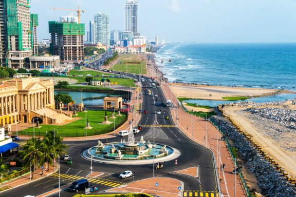 Aerial view of Colombo, Sri Lanka modern buildings with coastal promenade area. Car traffic during the day. Ocean waves.