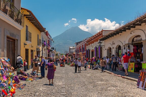 Bustling Street Market in Antigua with Volcano in the Background Crowded streets and vendors in Antigua near Guatemala City