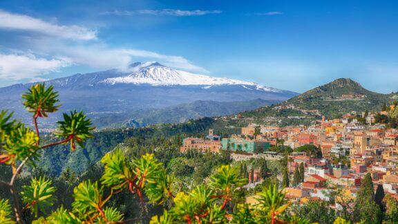 Mount Etna can be seen in the distance beyond the town of Taormina in Sicily, the largest region of Italy.