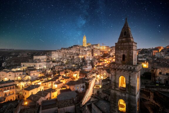 The old town of matera can be seen at night under a starry sky.