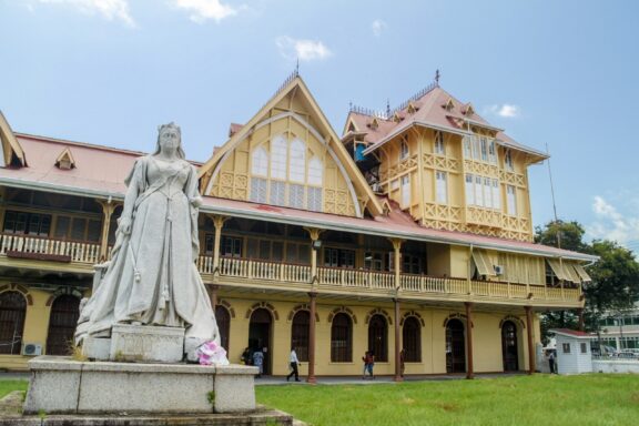 Statue in front of Victorian-style Building Statue of Queen Victoria, Pomenade Gardens, Georgetown