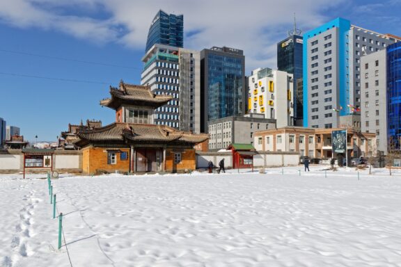 A traditional monastery in the city center contrasts with huge modern buildings in Ulaanbaatar, Mongolia.