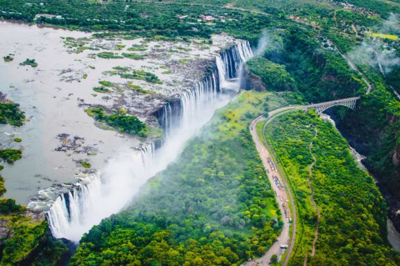 Aerial View of Victoria Falls with Lush Greenery and Mist Rising An aerial view of Victoria Falls between Zambia and Zimbabwe.