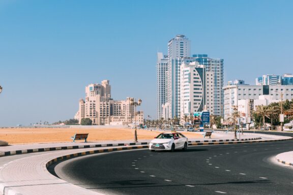 A taxi drives on a road next to the beach in Ajman, United Arab Emirates.