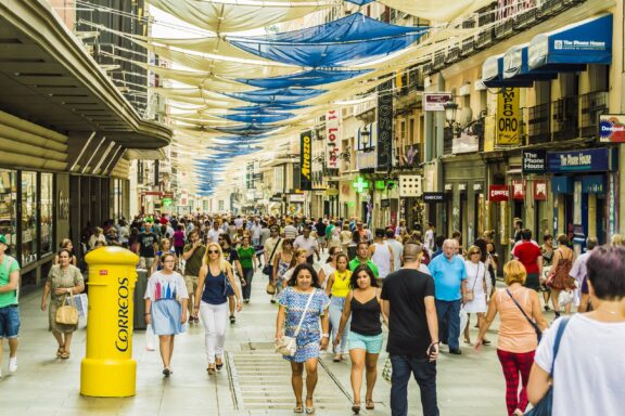 People commute and shop at a busy shopping street in Madrid