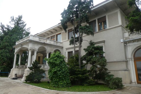 Exterior View of a Grand Mansion with Columns and Greenery Ceaușescu Mansion, constructed in the 1960s