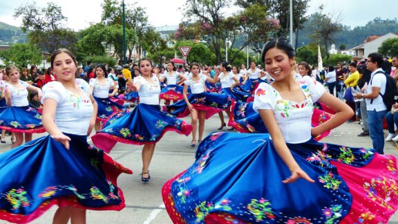 Colorful Street Parade with Dancers in Traditional Dress in Cuenca, Ecuador Women perform a traditional dance during a parade in Cuenca, Ecuador.