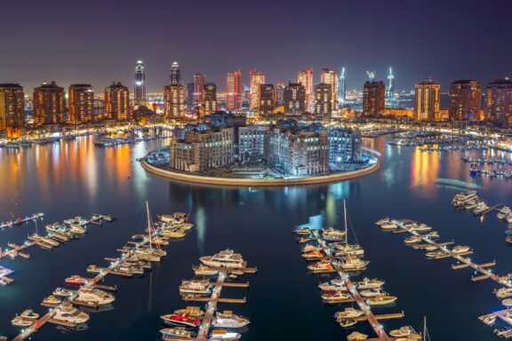 Boats sit at docks on the Pearl Island at night in Doha, Qatar.