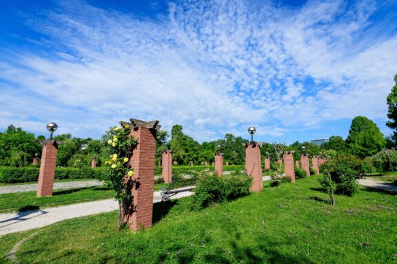 Park Pathway with Brick Pillars and Greenery under Blue Sky King Mihai I Park (formerly Herăstrău Park)
