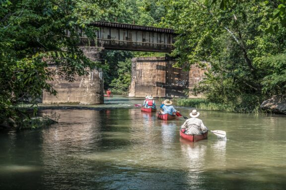 People in canoes paddle down the Cahaba River in Shelby County’s Helena, Alabama.