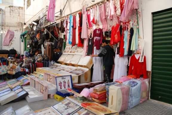 Street Market Stall with Textiles and Clothing Vendor selling clothes and art in the Souk al-Mushir, Tripoli