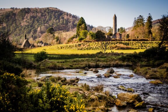 Scenic View of Wicklow Mountains with River and Historic Tower The ruins of Glendalough, nestled in the Wicklow Mountains