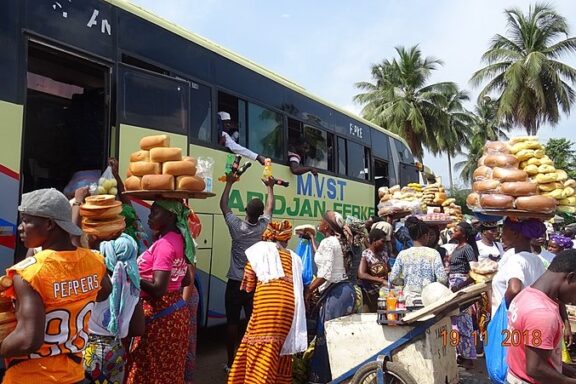 Yamoussoukro street vendors selling traditional bread to ongoing crowds