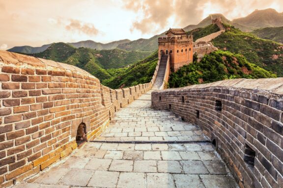 Green mountains can be seen on either side of the Great Wall of China. 