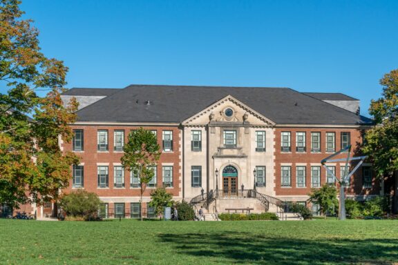 Classical Brick Building with Grand Entrance on a Sunny Day A green lawn stretches in front of the Castleman Building at the University of Connecticut in Tolland County.