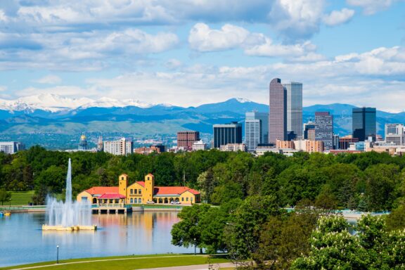 Panoramic View of Denver, Colorado Skyline with City Park and Rocky Mountains in the Background A view of a fountain in downtown Denver’s City Park.