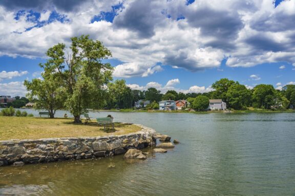 Serene Waterfront View at Cove Island Park, Stamford City A view of houses lining the water under a cloudy sky in Stamford, Connecticut’s Cove Island Park.