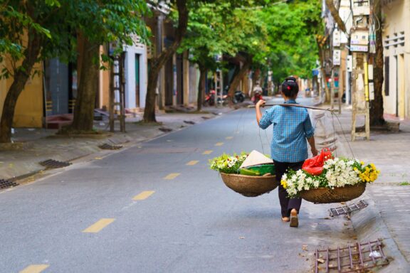 Street Vendor Carrying Baskets in Hanoi Hanoian woman with flowers to sell