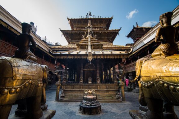 Golden Temple with Statues in Foreground Hiranya Varna Mahavihar, a golden pagoda-style temple in Patan