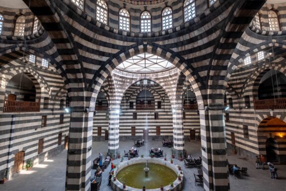Interior View of Khan As'ad Pasha Al-Azem with Arched Windows and Patterned Walls Khan As'ad Pasha, constructed in the 18th century, was a central marketplace and resting spot for travelers