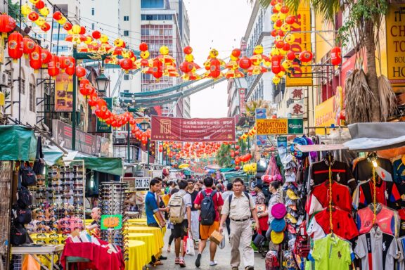 Bustling Street Market in Kuala Lumpur with Lantern Decorations Pedestrians stroll through bustling street with markets and shops, the lively essence of Kuala Lumpur