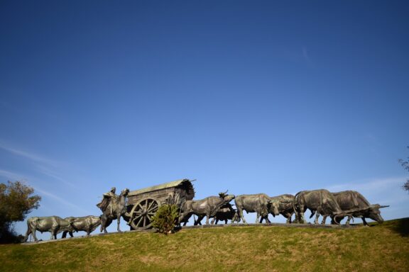 Bronze Oxen and Cart Monument Against Blue Sky La Carreta Monument, a bronze monument that honors the "carretas," or carts, used by the early settlers in Uruguay