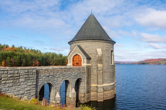 Autumnal View of the Historic Saville Dam with Stone Tower Overlooking a Reservoir A view of Saville Dam and surrounding water in Connecticut’s Litchfield County.