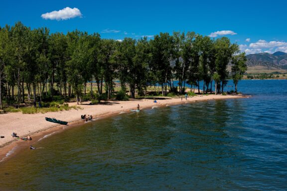 People gather near the shore of the Chatfield Reservoir on a sunny day in Colorado. 