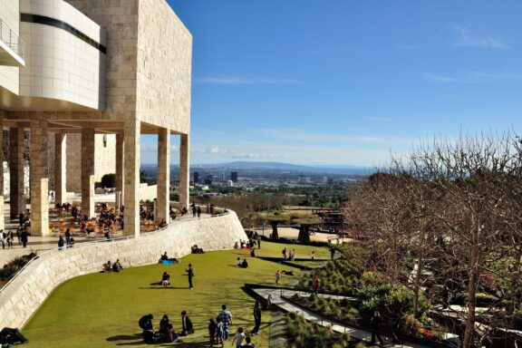 People sit on the lawn at the Getty Museum on a sunny day in Los Angeles.