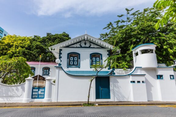 White Building with Blue Windows and Greenery Medhu Ziyaaraiy, the tomb of Moroccan scholar Abul Barakat Yoosuf Al Barbary