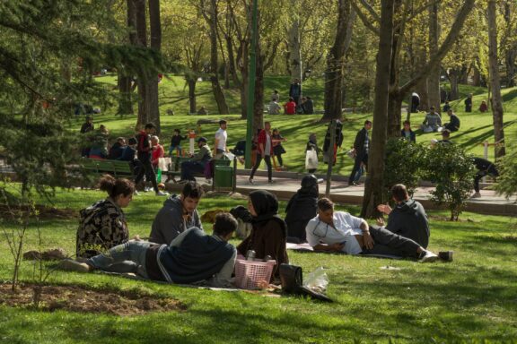 Locals socializing on the lush grasses of Mellat Park