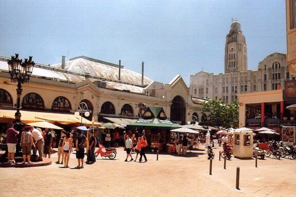 Bustling Market Square with Stalls and Towering Building in the Background Mercado del Puerto, known for its lively atmosphere and Uruguayan barbecue