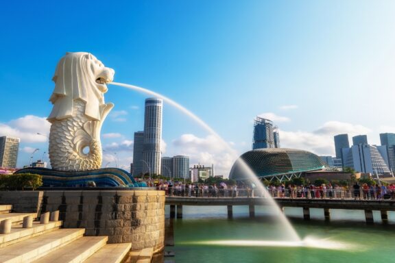 Merlion Statue Spraying Water with Singapore Skyline in Background The Merlion Sstatue in Merlion Park