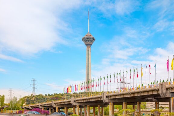 Milad Tower and Flags Against Blue Sky Milad Tower, Tehran's modern architectural icon
