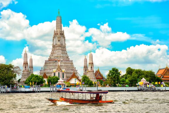 Boat on River in Front of Wat Arun Temple, Bangkok Wat Arun, named after Aruna, the Indian God of Dawn.