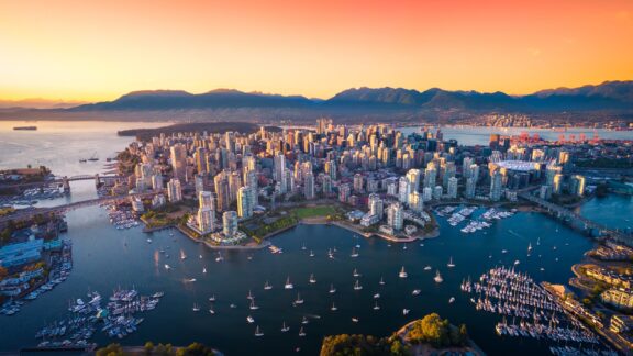 An aerial view of the city center of Vancouver, Canada, surrounded by water at sunset.