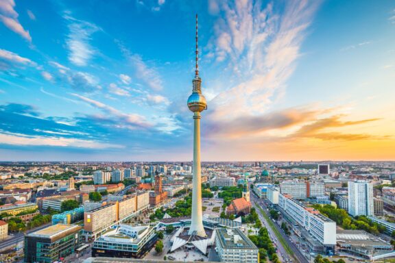 A view of the city of Berlin extending around the iconic TV Tower at sunset.